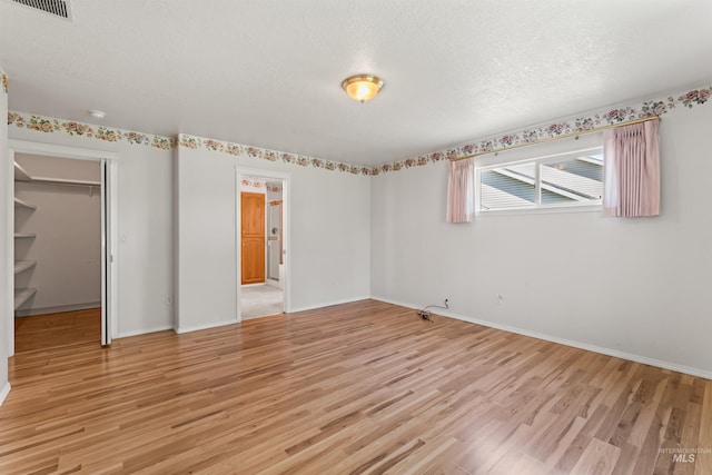 1728 S Labrador Pl, Meridian, ID 83642 - unfurnished bedroom with light wood-style flooring, a walk in closet, a textured ceiling, and a closet