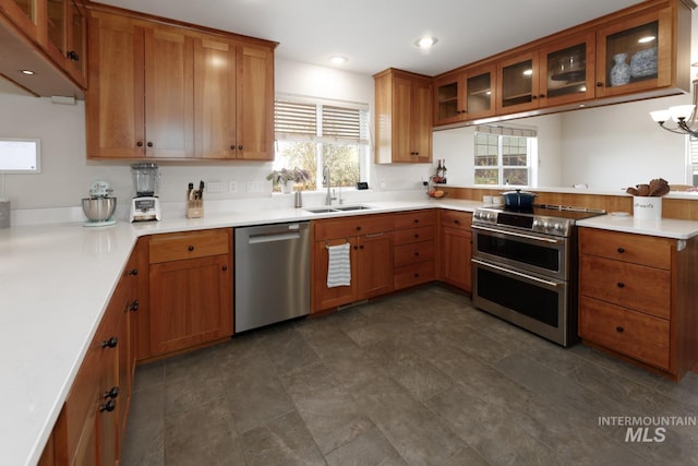 kitchen with appliances with stainless steel finishes, a sink, brown cabinetry, a peninsula, and glass insert cabinets