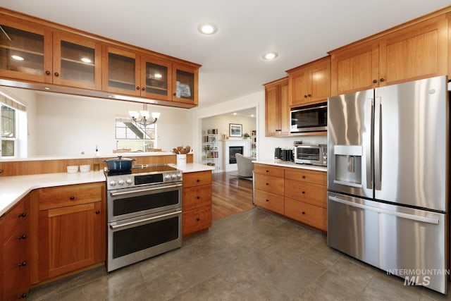 kitchen featuring an inviting chandelier, recessed lighting, brown cabinetry, and appliances with stainless steel finishes