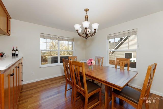 dining space with baseboards, plenty of natural light, wood finished floors, and a chandelier