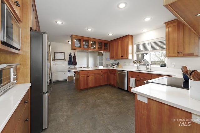 kitchen featuring a peninsula, a sink, appliances with stainless steel finishes, and brown cabinets