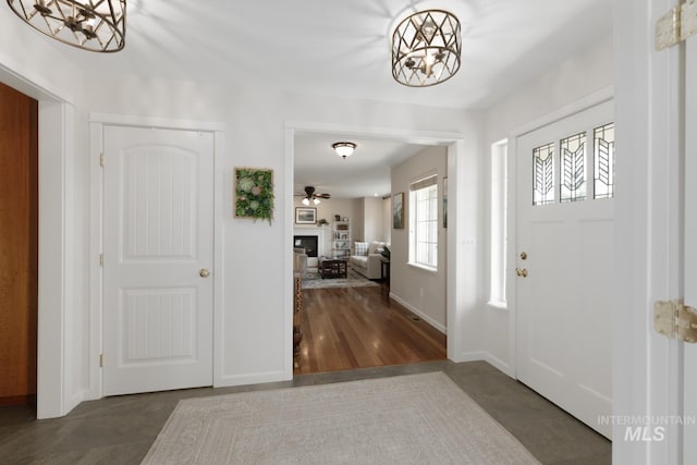 foyer with a glass covered fireplace, baseboards, and a chandelier