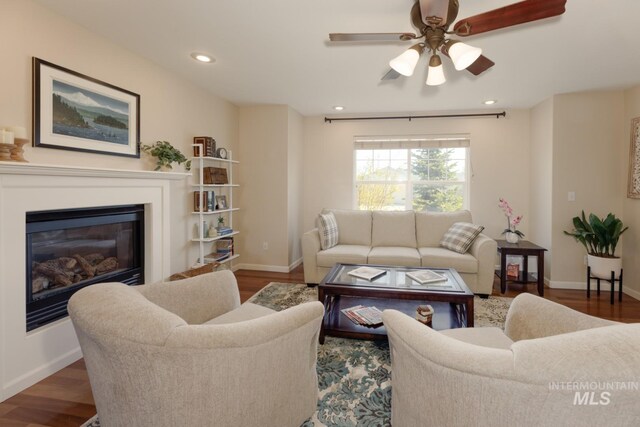 living area featuring a ceiling fan, baseboards, and wood finished floors