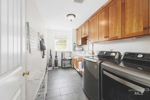 laundry area featuring a sink, dark tile patterned floors, cabinet space, and washing machine and clothes dryer