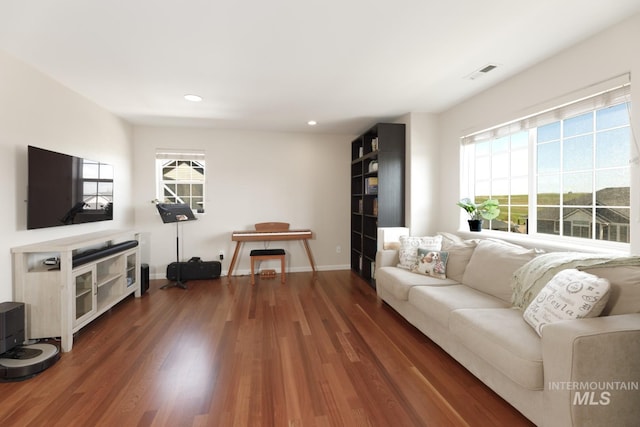living room featuring a healthy amount of sunlight, baseboards, wood finished floors, and visible vents