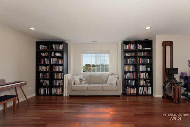 living area featuring recessed lighting, baseboards, wood finished floors, and bookshelves