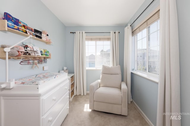 living area with baseboards, plenty of natural light, and light colored carpet