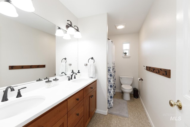 bathroom featuring double vanity, a sink, and toilet