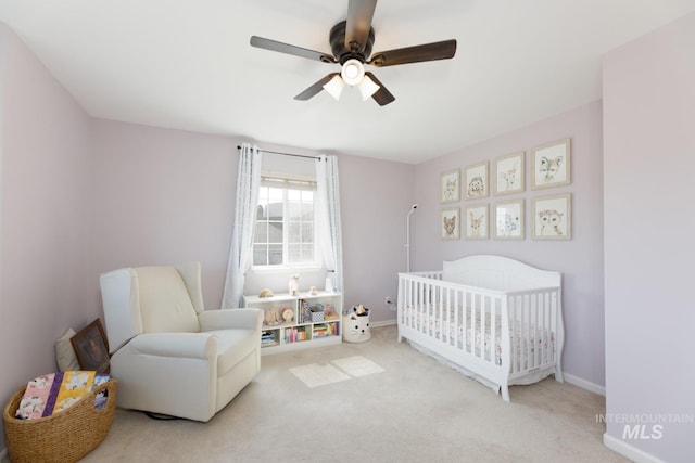 bedroom featuring carpet floors, a crib, ceiling fan, and baseboards