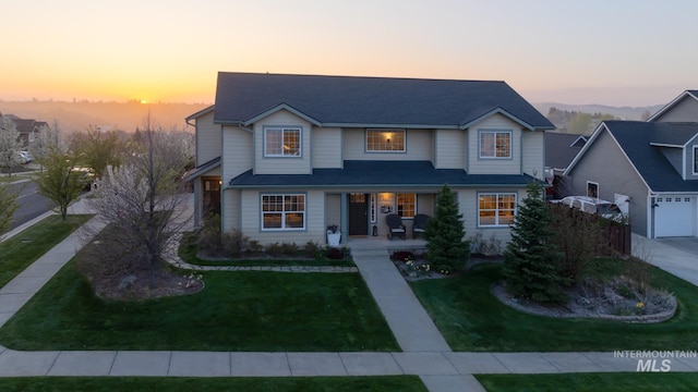 traditional home featuring a porch, a garage, and a front yard