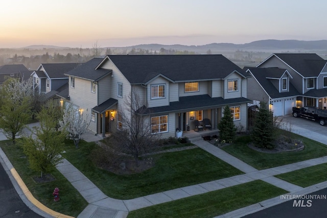view of front of property with an attached garage, a lawn, a mountain view, and driveway
