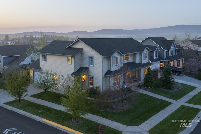 view of front facade with a lawn, a mountain view, and concrete driveway