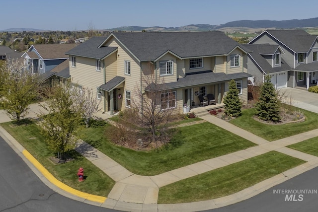 traditional-style home with a garage, a porch, a mountain view, driveway, and a residential view