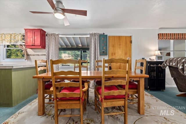 dining space with a ceiling fan and light colored carpet