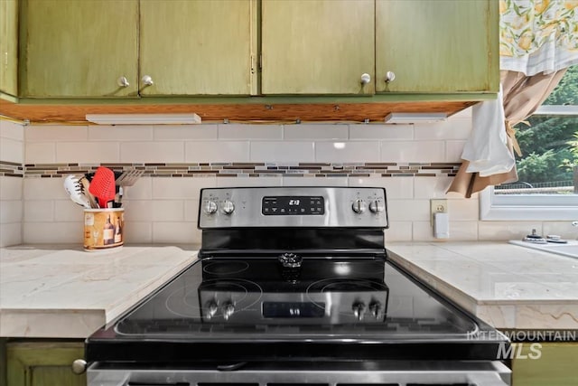 kitchen featuring electric stove, decorative backsplash, light countertops, and green cabinetry