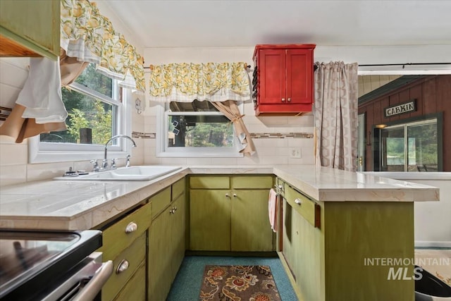 kitchen with a peninsula, backsplash, a sink, and light countertops