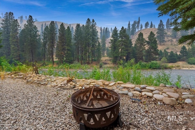 view of yard with a forest view, an outdoor fire pit, and a mountain view