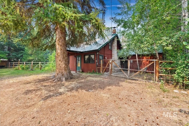 view of side of home featuring metal roof, a chimney, and fence