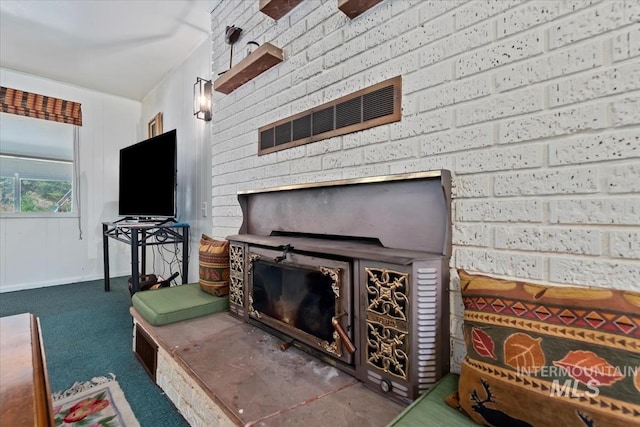 carpeted living area with visible vents, a fireplace, and brick wall