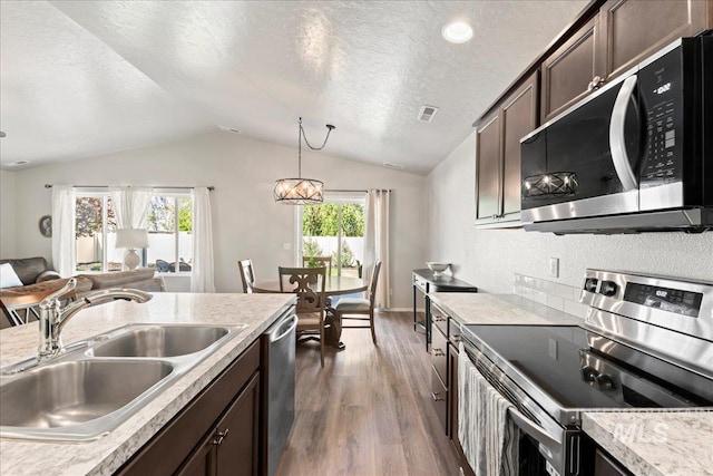 kitchen with stainless steel appliances, a sink, lofted ceiling, dark wood-style floors, and a textured ceiling