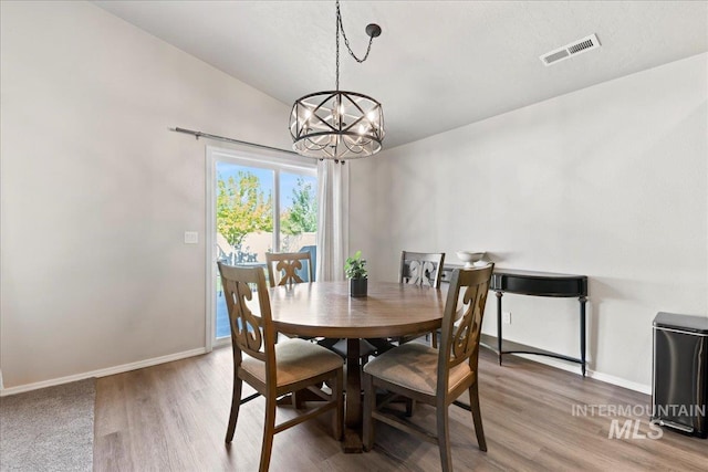 dining space with a chandelier, light wood finished floors, and baseboards