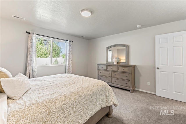 bedroom with light carpet, baseboards, and a textured ceiling