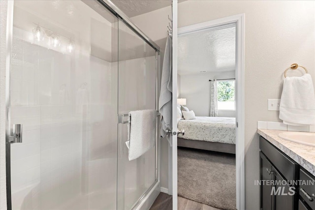 bathroom with ensuite bath, a stall shower, a textured ceiling, vanity, and wood finished floors