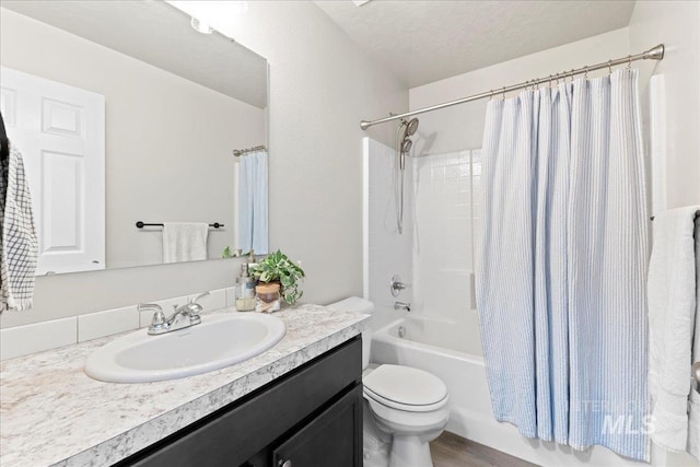 bathroom featuring toilet, vanity, shower / bath combo with shower curtain, and a textured ceiling