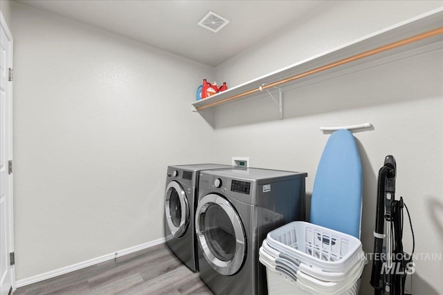 laundry area featuring separate washer and dryer, wood finished floors, and baseboards