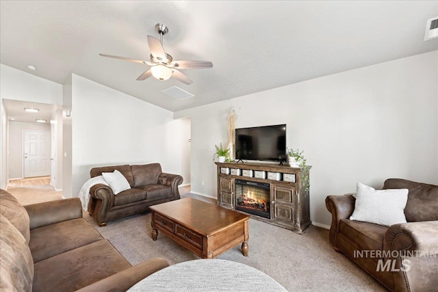 carpeted living room with vaulted ceiling, a glass covered fireplace, baseboards, and a ceiling fan