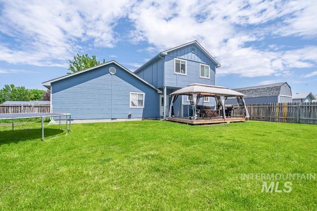 1010 Jonathan St, Fruitland, ID 83619 - rear view of house with a trampoline, a gazebo, a fenced backyard, a deck, and board and batten siding