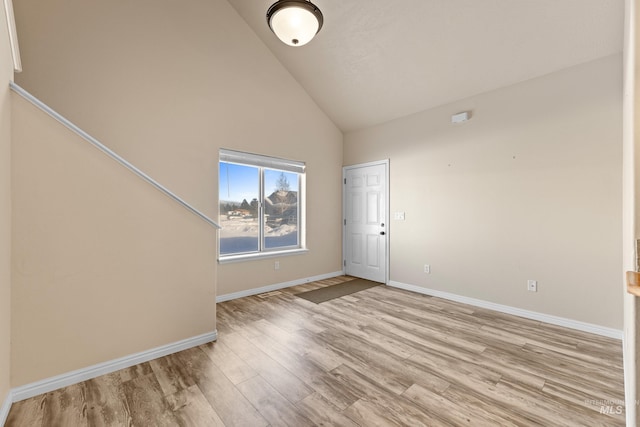 empty room featuring high vaulted ceiling and light wood-type flooring