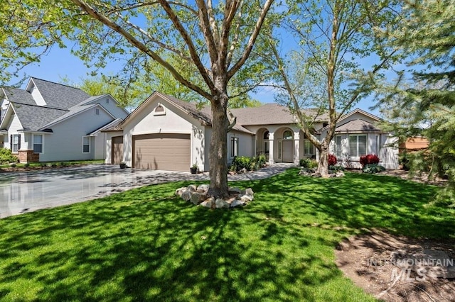 view of front facade with an attached garage, driveway, a front yard, and stucco siding