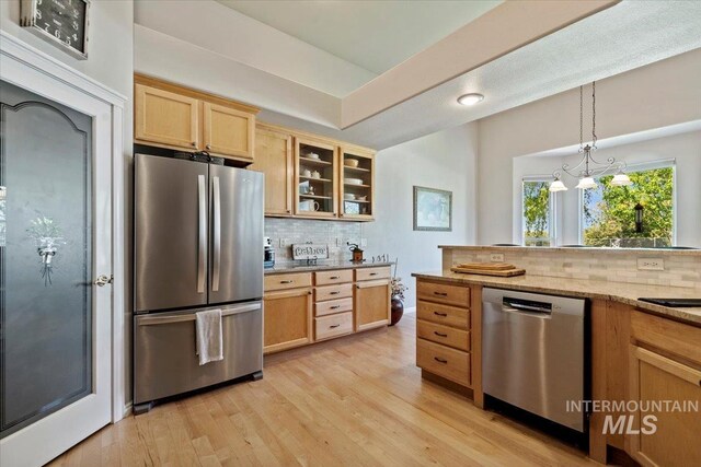 kitchen featuring appliances with stainless steel finishes, backsplash, glass insert cabinets, and light wood-style flooring