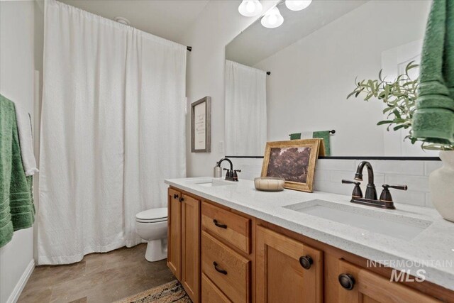 bathroom with backsplash, toilet, and double vanity