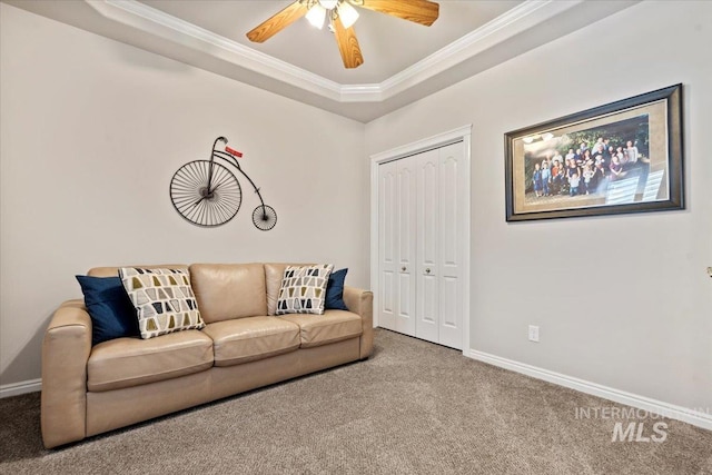 living room featuring carpet floors, crown molding, baseboards, a tray ceiling, and ceiling fan