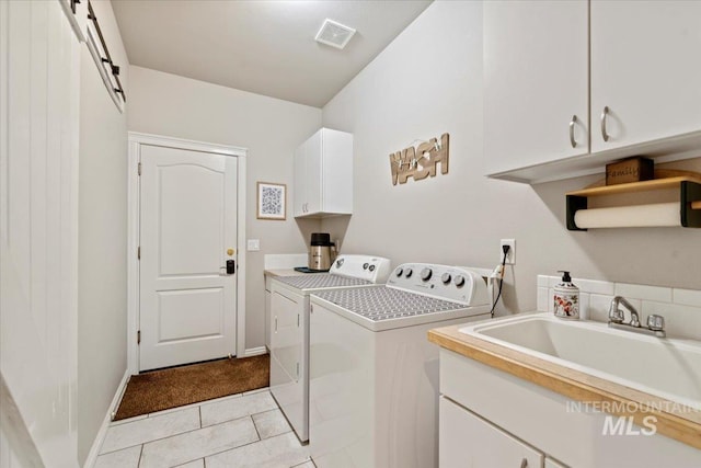 laundry area with separate washer and dryer, cabinet space, light tile patterned floors, and baseboards