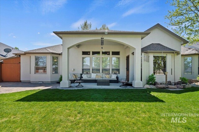 rear view of property featuring an outdoor hangout area, stucco siding, a patio area, and a yard