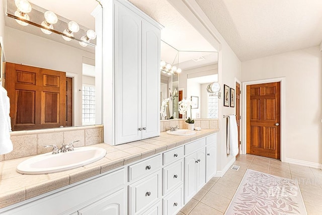 full bath featuring double vanity, tile patterned flooring, and a sink