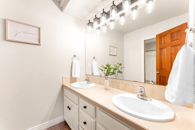 bathroom with double vanity, a sink, and baseboards