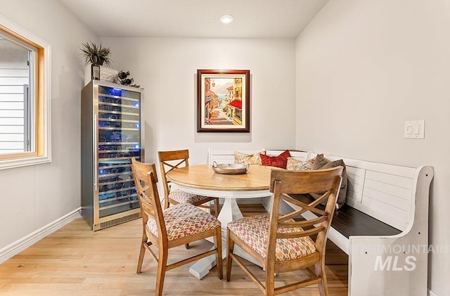 dining space featuring wine cooler, light wood finished floors, breakfast area, recessed lighting, and baseboards