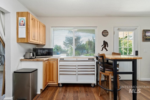 12456 S Lonnie Ln, Kuna, ID 83634 - kitchen featuring black microwave, dark wood finished floors, light countertops, a desk, and light brown cabinets