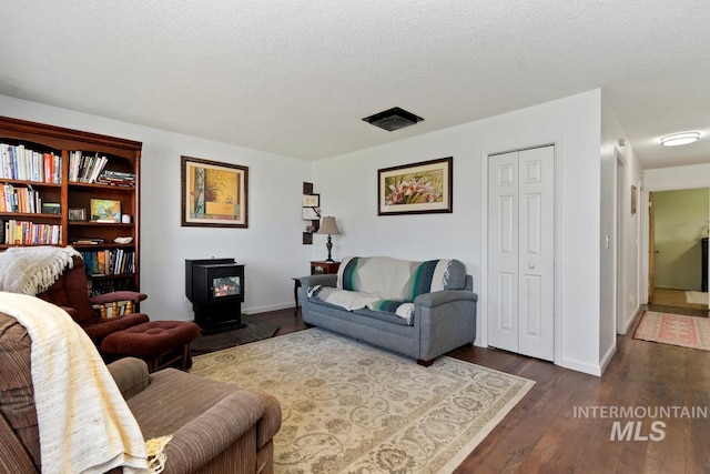12456 S Lonnie Ln, Kuna, ID 83634 - living area with a wood stove, dark wood finished floors, baseboards, and a textured ceiling
