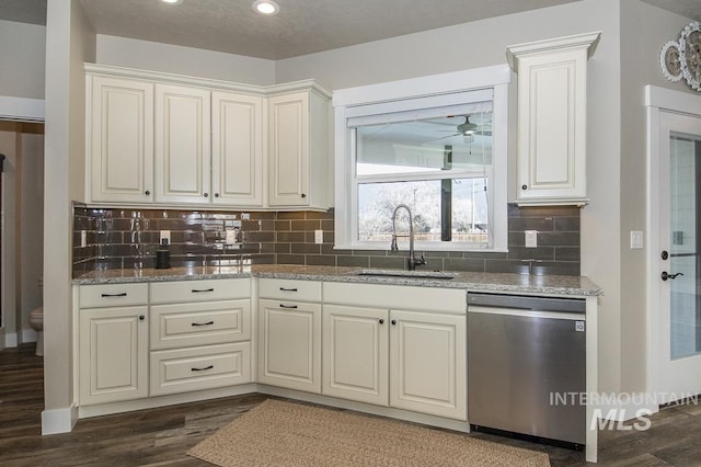 kitchen with sink, stone countertops, dark wood-type flooring, stainless steel dishwasher, and tasteful backsplash