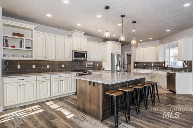 kitchen with appliances with stainless steel finishes, white cabinetry, a center island, and light stone counters