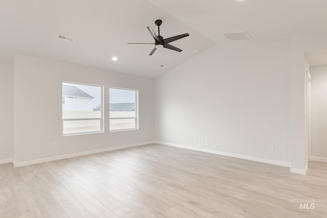 spare room with a ceiling fan, vaulted ceiling, light wood-style floors, and visible vents