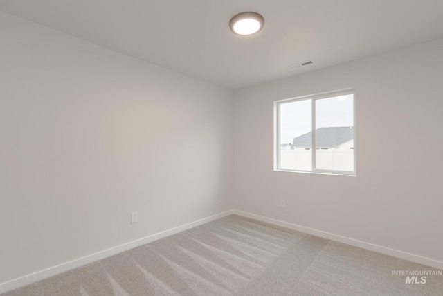 unfurnished room featuring visible vents, light colored carpet, and baseboards