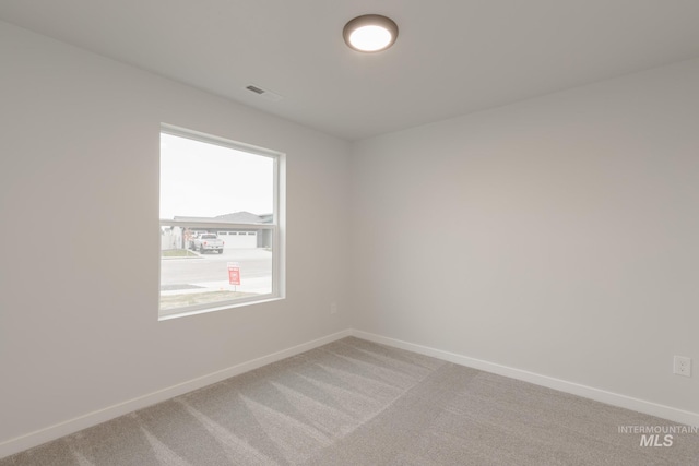 unfurnished room featuring baseboards, light carpet, and visible vents