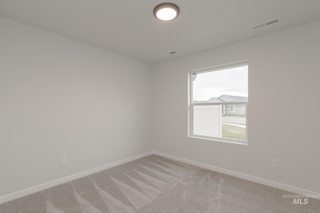 unfurnished room with light carpet, visible vents, and baseboards