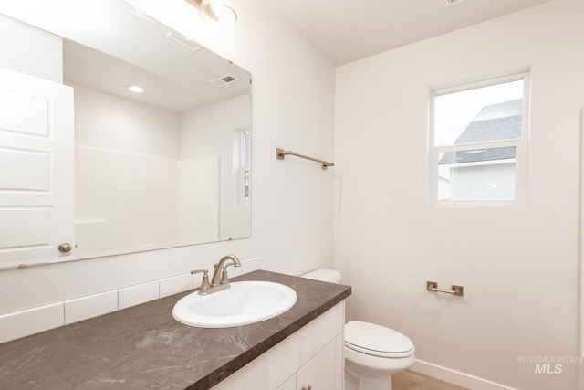 bathroom with vanity, toilet, baseboards, and visible vents